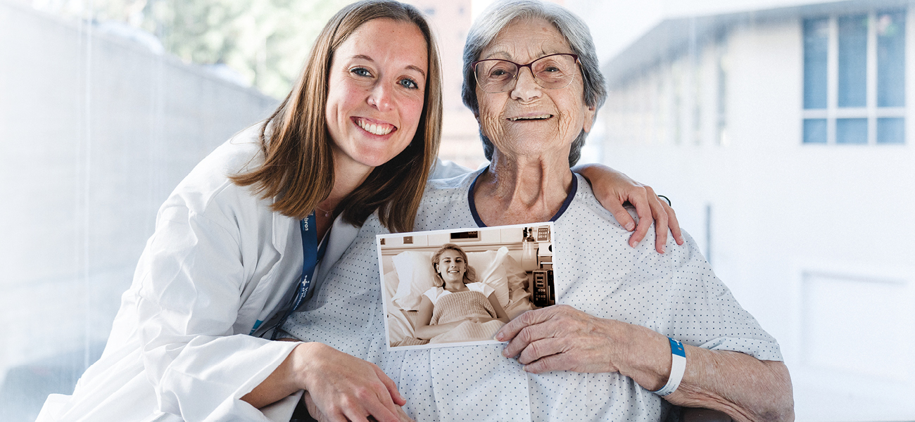 Professional i pacient de Vall d'Hebron sostenint una fotografia antiga per celebrar els 70 anys de l'Hospital