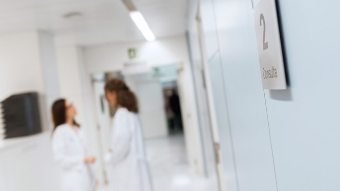 Dos professionals del Servei d'Oncologia Mèdica parlant davant d'una consulta del Servei